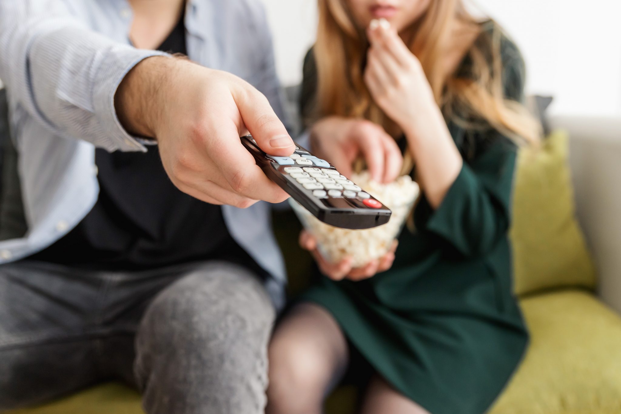 A man and a woman sat on a sofa holding a TV remote
